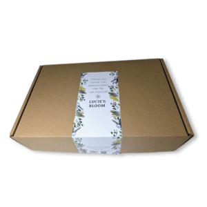 Custom floral rectangular sticker with Lucie’s Bloom branding placed on a kraft cardboard gift box