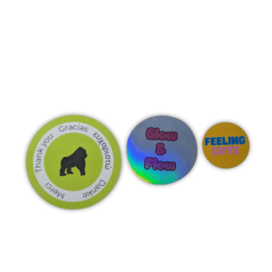 Three custom circular stickers: one green thank-you sticker with a gorilla logo, one holographic “Glow & Flow” sticker, and one orange “Feeling Cute” sticker